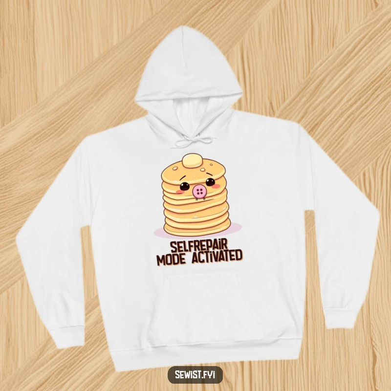 Funny pancake hoodie depicting a wobbly stack trying to sew a giant button onto itself, a warm and humorous apparel choice.