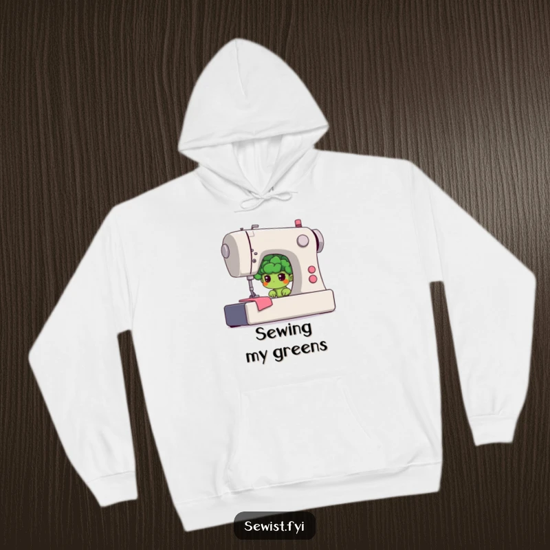 Funny broccoli hoodie featuring a shy floret hiding behind a giant sewing machine, a warm and humorous apparel choice.